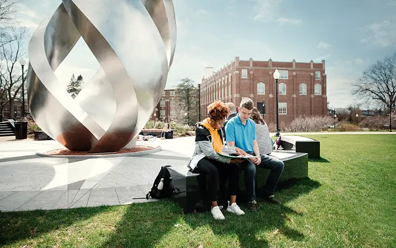 two students studying in front of the calabria torch 