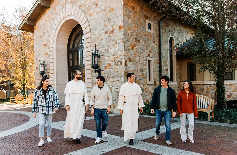students walking with priests near the chapel