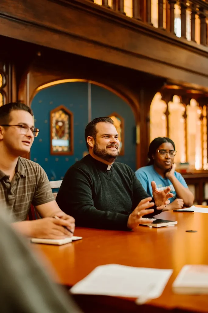 students with a priest in a classroom