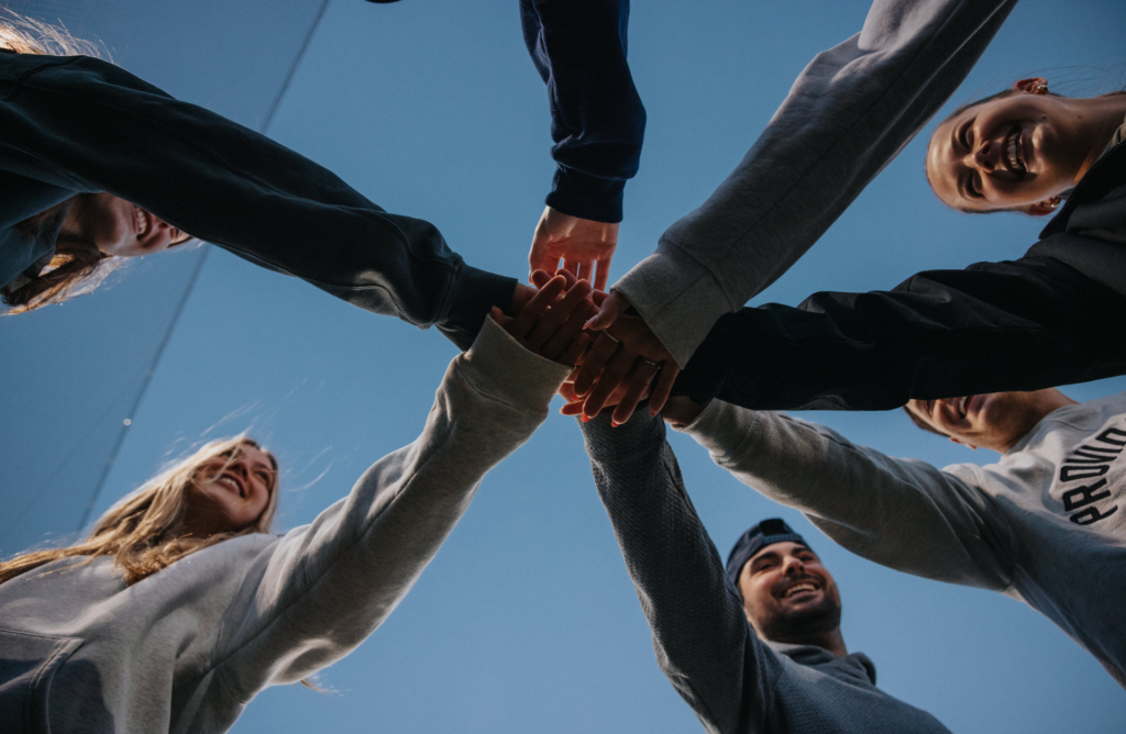 Students put their hands in to celebrate a kickball victory